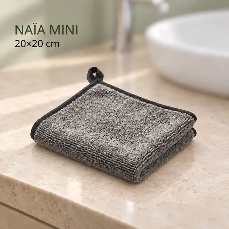 Chiffon Naïa L de 20 × 20 cm, gris à bordure noire, plié près d’un lavabo.